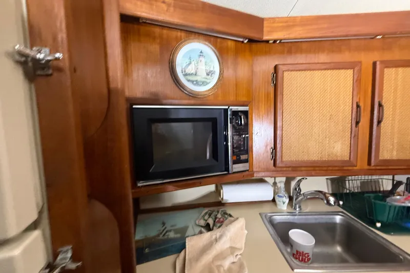 Slide: The Image of 1984 Viking 44 Motor Yacht kitchen with microwave, wooden cabinets, and sink. - 57