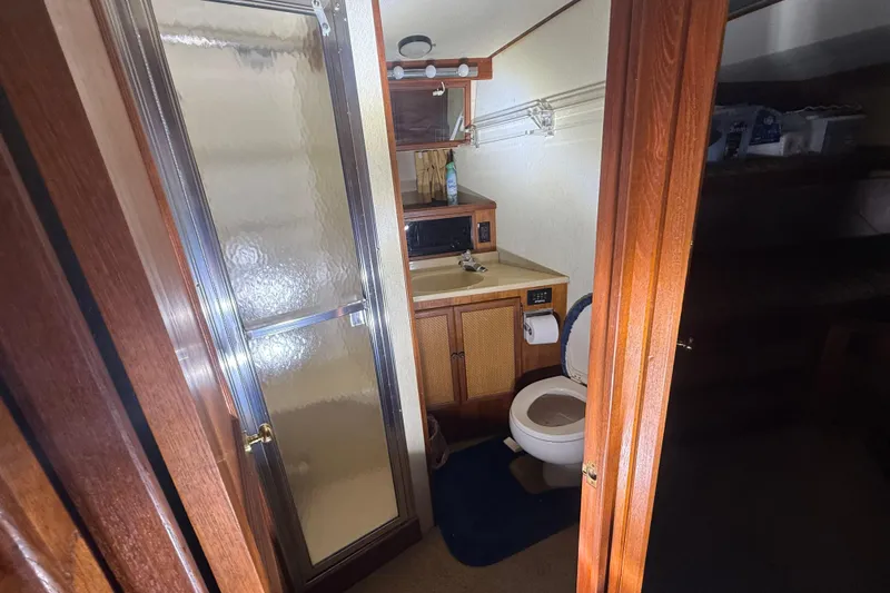 Slide: The Image of 1984 Viking 44 Motor Yacht bathroom with shower, toilet, and wooden cabinetry. - 59
