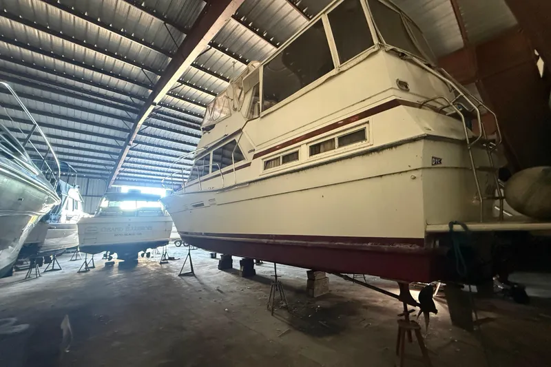 Slide: The Image of 1984 Viking 44 Motor Yacht in storage, elevated on stands inside a metal-roofed warehouse. - 6