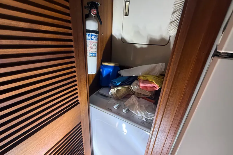 Slide: The Image of Laundry area on 1984 Viking 44 Motor Yacht with fire extinguisher and folded towels. - 66