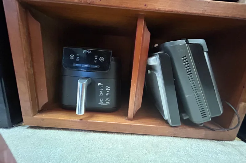 Slide: The Image of Ninja air fryer and kitchen appliances stored in wooden cabinet on Ocean Alexander 50 Pilothouse. - 17