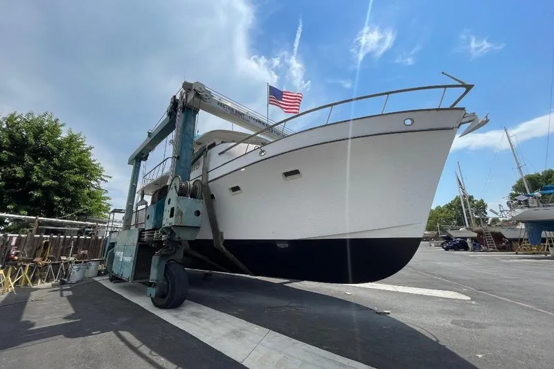 Slide: The Image of 1981 Ocean Alexander 50 Pilothouse yacht on a lift, with American flag, under blue sky. - 43