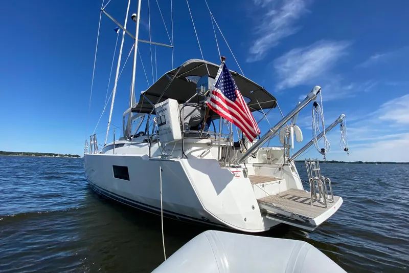 Slide: The Image of 2019 Jeanneau 51 sailboat with American flag on calm waters under blue sky. - 15