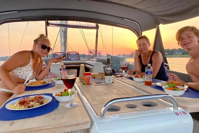 Slide: The Image of Family dining on Jeanneau 51 sailboat at sunset, enjoying pasta and wine, 2019 model. - 42