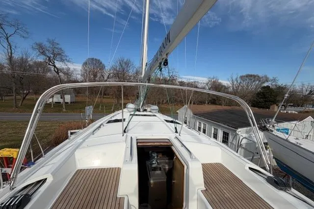 Slide: The Image of 2019 Jeanneau 51 sailboat deck with open hatch, surrounded by trees and buildings. - 47