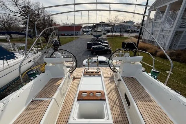 Slide: The Image of 2019 Jeanneau 51 yacht deck with dual steering wheels and wooden seating. - 49