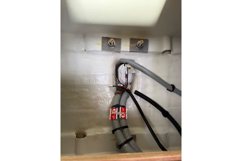 Slide: The Image of Interior view of 2019 Jeanneau 51 yacht's technical compartment with wiring and hoses. - 56