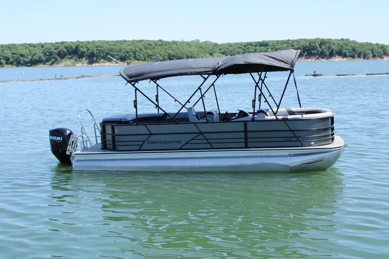 Slide: The Image of 2024 Berkshire 24CL CTS pontoon boat on a serene lake with lush green shoreline. - 3