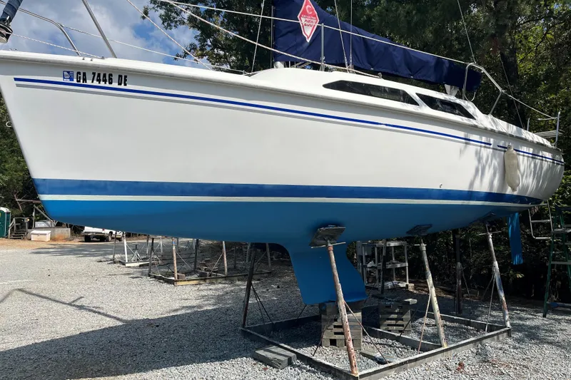 Slide: The Image of 2004 Catalina 250 WK sailboat on stands, white hull with blue accents, outdoors. - 10