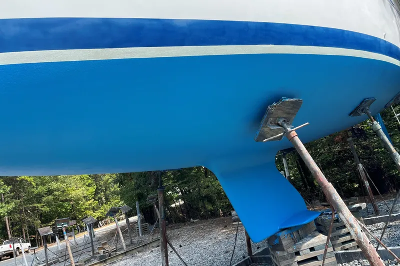Slide: The Image of Blue hull of a 2004 Catalina 250 WK sailboat on stands, outdoors. - 11