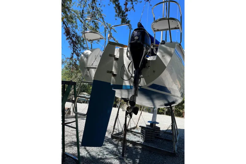 Slide: The Image of 2004 Catalina 250 WK sailboat on stands, viewed from the rear under a clear blue sky. - 12