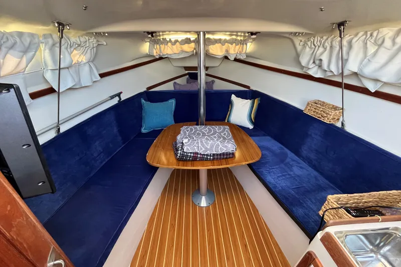Slide: The Image of Interior of 2004 Catalina 250 WK sailboat with blue seating and wooden table. - 4