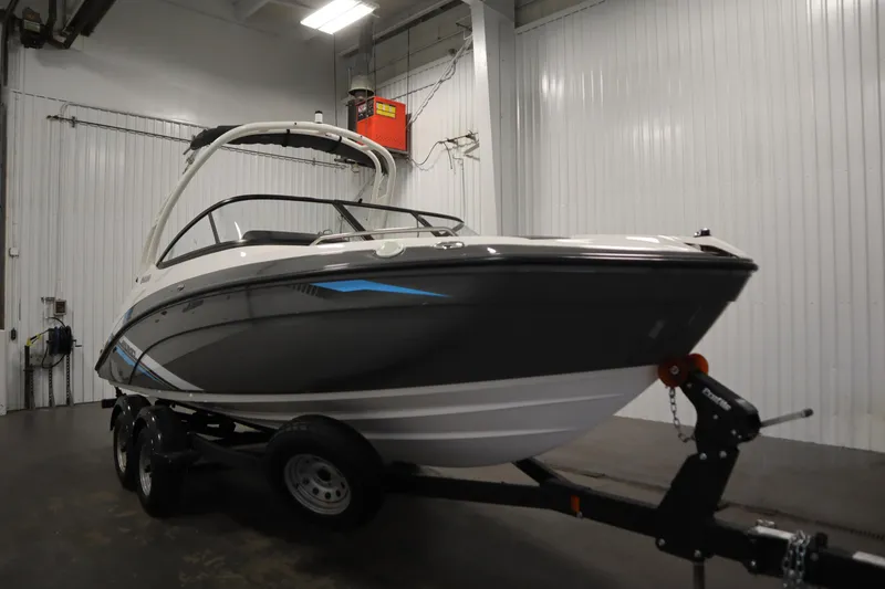 Slide: The Image of 2020 Yamaha Boats AR210 in indoor storage, showcasing sleek design and trailer. - 2