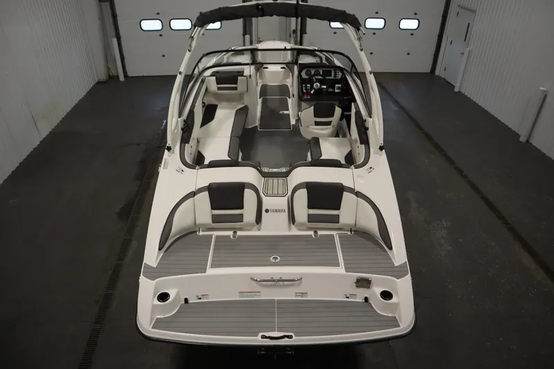 Slide: The Image of 2020 Yamaha Boats AR210 interior view, showcasing seating and dashboard in a garage setting. - 9