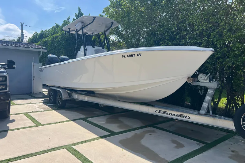 The Image of 1990 Intrepid 28 Open boat on trailer, parked in driveway, surrounded by greenery. - 1