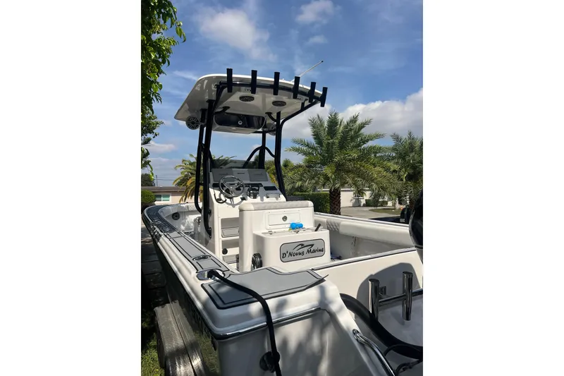 Slide: The Image of 1990 Intrepid 28 Open boat with T-top, parked near palm trees under a blue sky. - 4