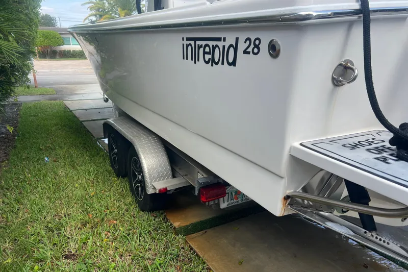 Slide: The Image of 1990 Intrepid 28 Open boat on trailer, parked on grass. - 5