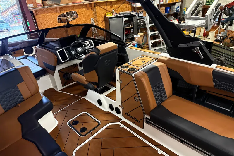Slide: The Image of 2022 Malibu Wakesetter 25 LSV interior with luxurious brown and black seating, modern dashboard. - 11