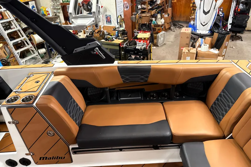 Slide: The Image of 2022 Malibu Wakesetter 25 LSV interior with tan and black seating in a workshop. - 12