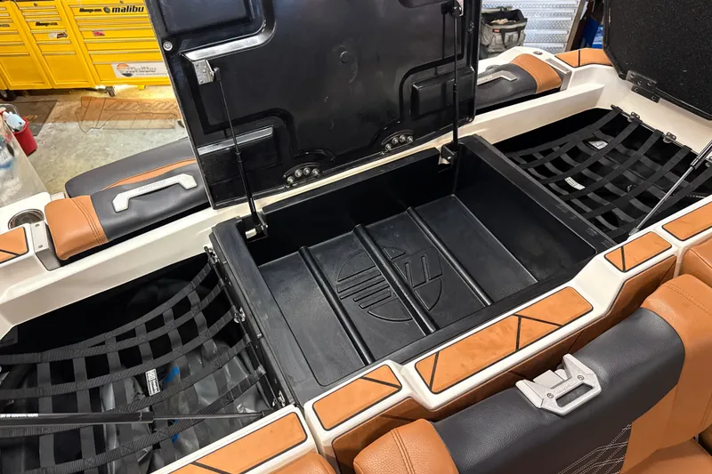 Slide: The Image of 2022 Malibu Wakesetter 25 LSV storage compartment with open lid and cushioned seating. - 16
