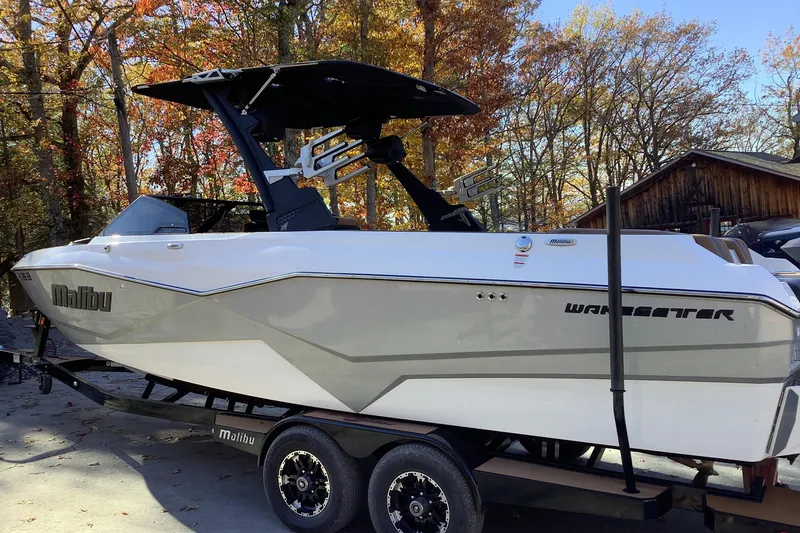 Slide: The Image of 2022 Malibu Wakesetter 25 LSV boat on trailer, surrounded by autumn trees. - 2