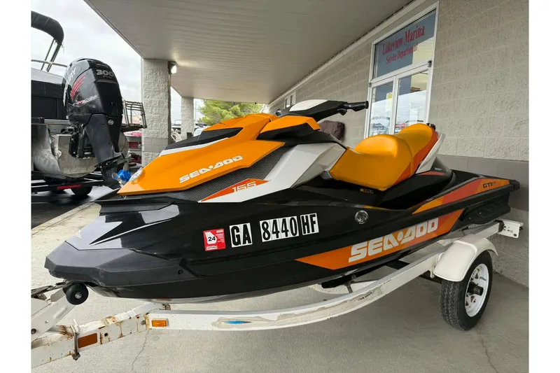 Slide: The Image of 2018 Seadoo GTI SE 155 jet ski in orange and black on a trailer at a marina. - 11