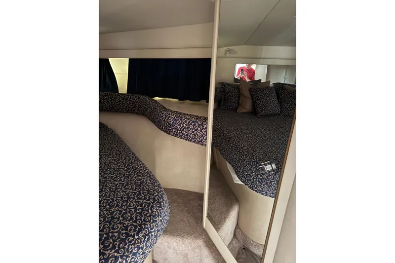 Slide: The Image of 1997 Sea Ray 370 Aft Cabin interior with patterned bedding and mirrored closet. - 38