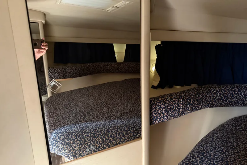 Slide: The Image of 1997 Sea Ray 370 Aft Cabin interior with patterned bedding and dark curtains. - 40