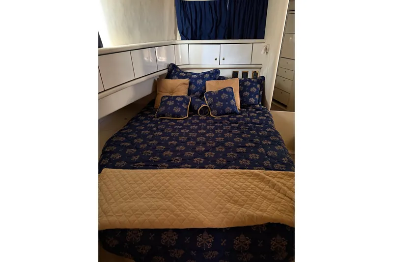 Slide: The Image of 1997 Sea Ray 370 Aft Cabin bedroom with blue patterned bedding and white cabinets. - 49