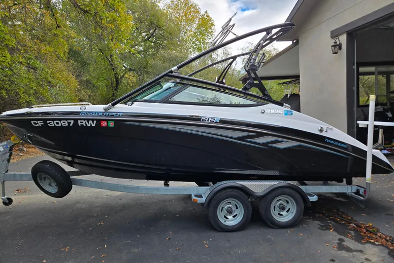 Slide: The Image of 2013 Yamaha Boats 212X on trailer, parked outdoors near a house. - 1