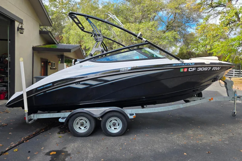 Slide: The Image of 2013 Yamaha Boats 212X on trailer, parked outdoors near a garage. - 14