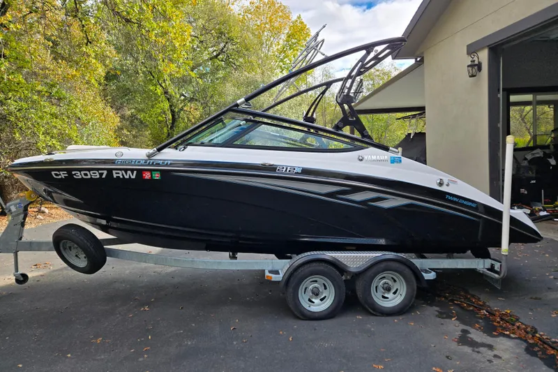Slide: The Image of 2013 Yamaha Boats 212X on trailer, parked outdoors near a garage. - 16