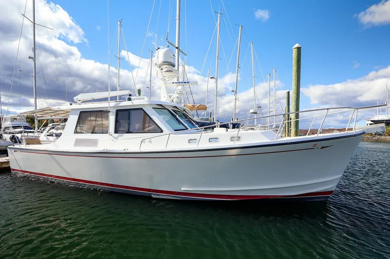 The Image of 2005 New England Boatworks Downeast Sedan docked in a marina under a blue sky. - 0