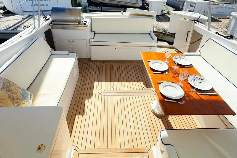 Slide: The Image of Luxurious 2005 New England Boatworks Downeast Sedan with elegant dining setup on deck. - 18