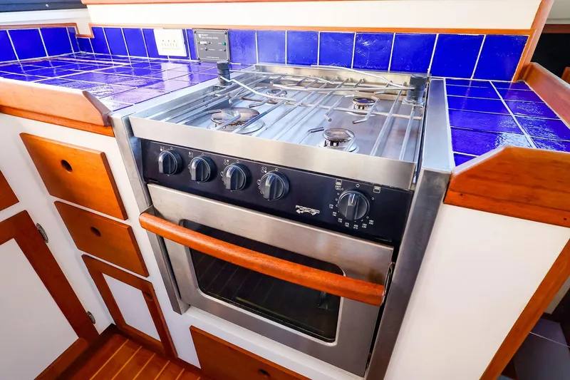 Slide: The Image of Stainless steel stove in 2005 New England Boatworks Downeast Sedan, with blue tiled countertop. - 21