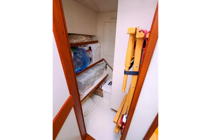 Slide: The Image of Storage area inside 2005 New England Boatworks Downeast Sedan, featuring shelves and folding chairs. - 33