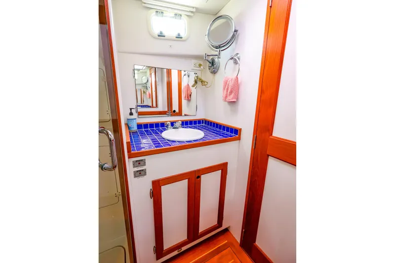 Slide: The Image of Luxurious 2005 New England Boatworks Downeast Sedan bathroom with blue-tiled sink and wooden accents. - 40