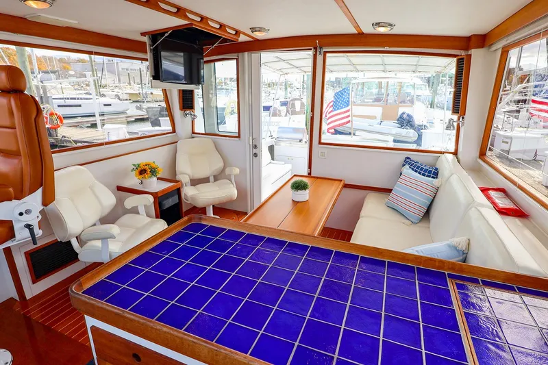 Slide: The Image of Interior of 2005 New England Boatworks Downeast Sedan with blue-tiled table and white seating. - 20
