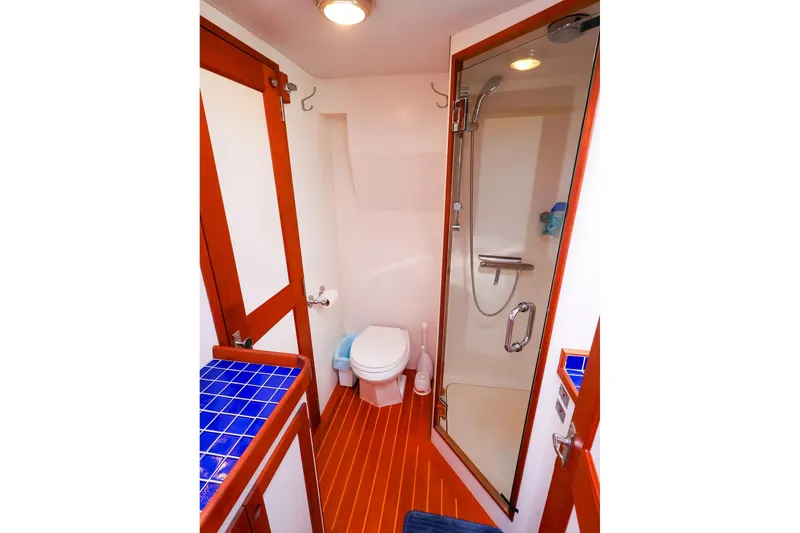 Slide: The Image of Luxurious 2005 New England Boatworks Downeast Sedan bathroom with shower and blue-tiled vanity. - 38