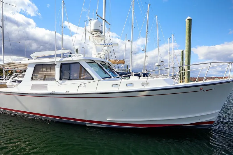Slide: The Image of 2005 New England Boatworks Downeast Sedan docked in a marina under a blue sky. - 43