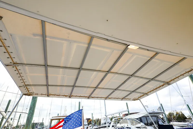 Slide: The Image of 2005 New England Boatworks Downeast Sedan canopy with American flag in marina setting. - 7