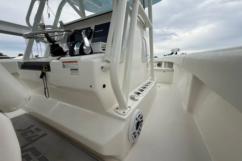 Slide: The Image of 2022 SeaVee 270Z boat interior with steering console and rod holders, under cloudy sky. - 31