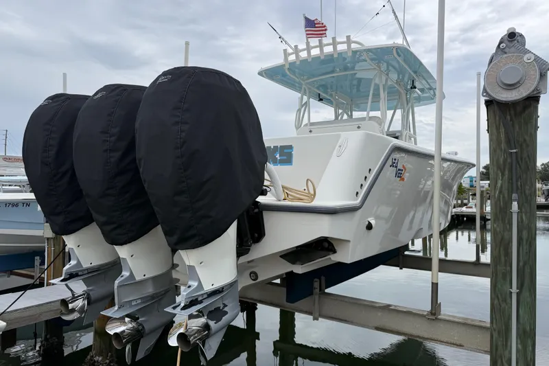 Slide: The Image of 2022 SeaVee 270Z boat with triple outboard engines on a lift, docked at a marina. - 40