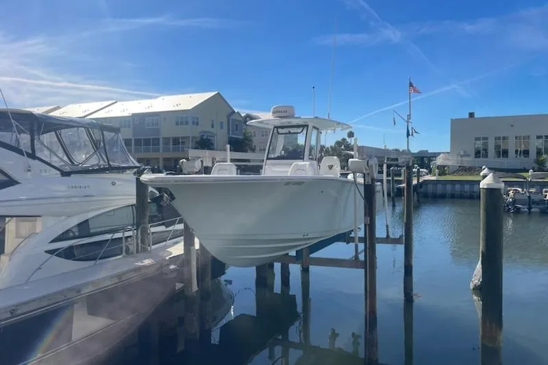 Slide: The Image of 2025 Sportsman Heritage 261 Center Console boat docked at a marina under clear blue skies. - 0