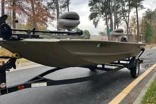 Slide: The Image of 2025 Tracker Grizzly 1754 AWL boat on trailer, parked on a road with trees in background. - 7