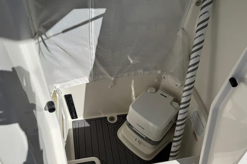 Slide: The Image of 2026 Sailfish 252 CC boat interior with portable toilet and privacy curtain. - 12