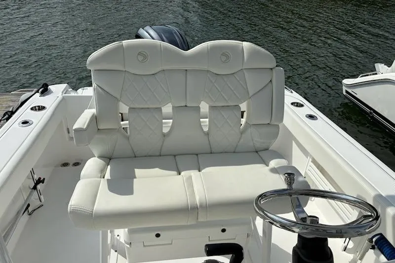 Slide: The Image of 2022 Edgewater 230CC boat with white cushioned seating and steering wheel on water. - 10