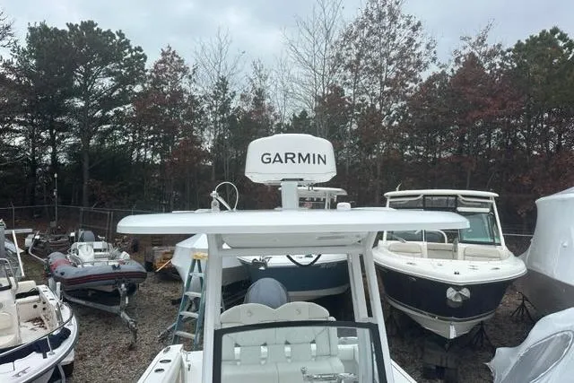 Slide: The Image of 2022 Edgewater 230CC boat with Garmin radar, parked among other boats in a wooded area. - 21
