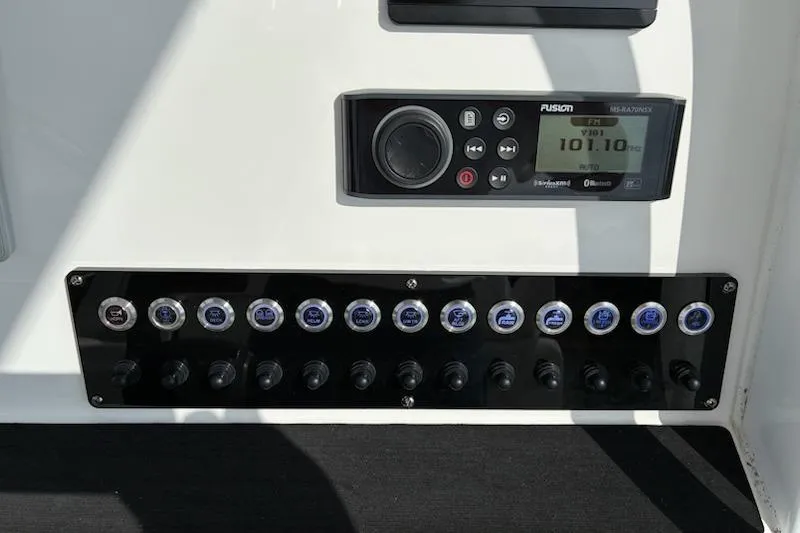 Slide: The Image of Control panel of 2022 Edgewater 230CC boat with Fusion stereo system and switches. - 6
