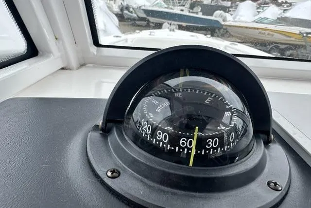 Slide: The Image of Compass on 2022 Edgewater 230CC boat dashboard, with marina view through window. - 7